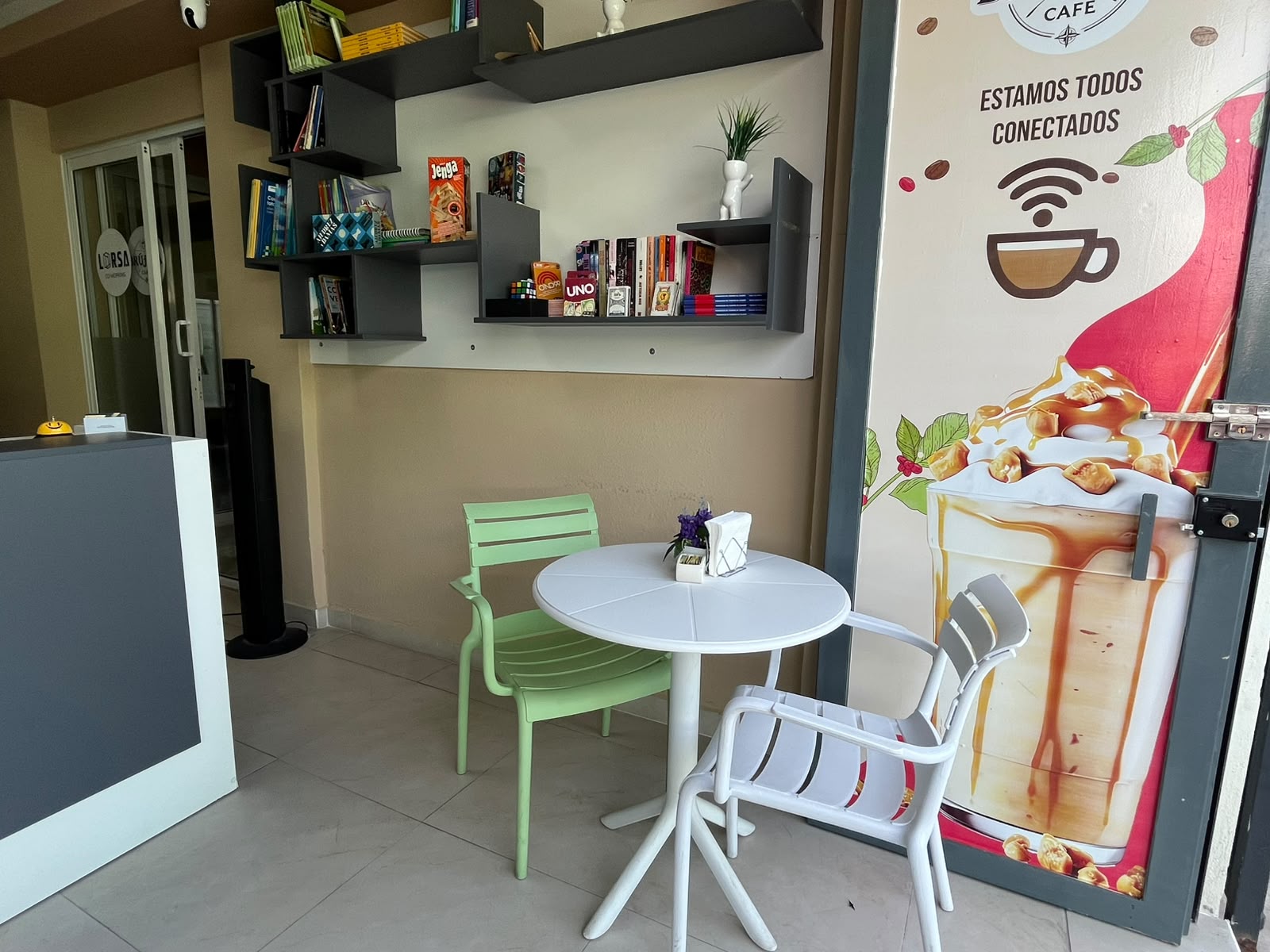 Zona de mesas, repisa de libros y juegos